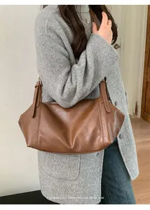 Sac fourre-tout rétro en cuir marron porté avec un manteau gris pour un look chic minimaliste