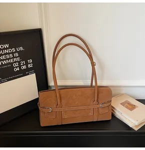 Detail of vintage brown faux leather shoulder bag featuring silver buckles and textured finish