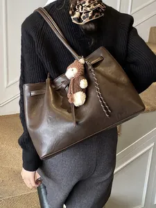 Deep brown faux leather tote bag with side drawstrings and plush bear charm on model