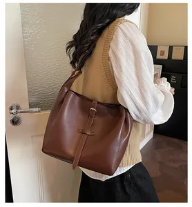 Close-up of brown matte leather tote bag with decorative buckle strap for daily commute