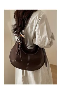 Détail du sac hobo marron foncé avec surpiqûres contrastées et pompon sur le mannequin