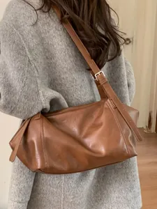 Grand sac cabas marron rétro avec bandoulière réglable sur un modèle de manteau gris