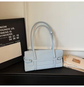 Detail view of light blue leather handbag with metal buckle and thin straps