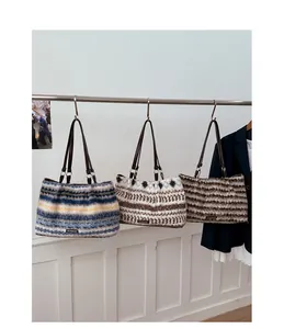 Detailed view of striped and plaid faux fur tote bags hanging on a display wall
