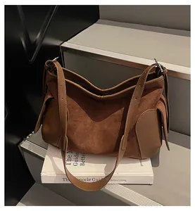 Détail du sac cabas vintage en daim marron et cuir sur un fond au style minimaliste