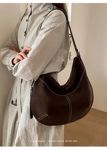 Détail du sac hobo en cuir marron foncé avec surpiqûres contrastées et style rétro épuré