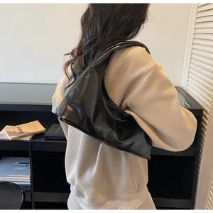 Rear view of a black glossy hobo bag worn on the shoulder with a minimalist moon shape