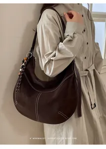 Détail du grand sac hobo marron foncé avec surpiqûres et pendentif à pampilles