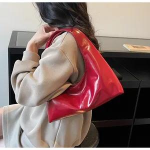 Detail of red patent leather shoulder bag with glossy finish and sleek triangular design