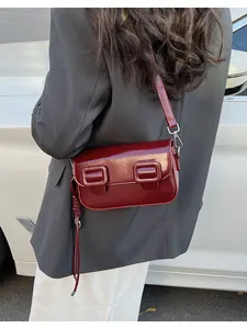 Detail of dark red glossy baguette bag featuring double square buckles and patent leather finish