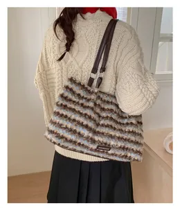 Detail of plush striped tote bag featuring soft faux fur texture and brown leather strap