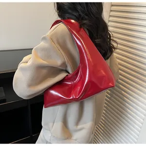 Detailed view of glossy red patent leather hobo bag worn by model on shoulder