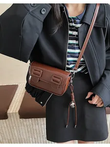 Detail of dark brown retro baguette bag with glossy PU leather and buckle accents