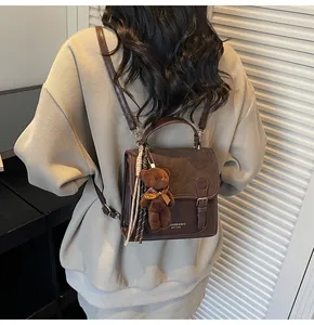 Detalle de un bolso vintage marrón con amuleto de oso, llevado por una modelo en estudio