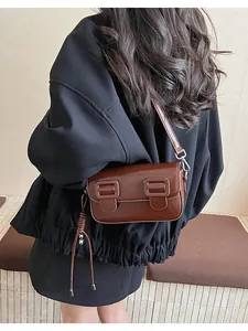 Detail view of a vintage dark brown baguette bag with decorative fringe and glossy finish