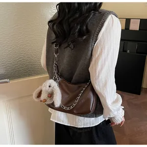 Detail of vintage brown crescent tote bag with silver chain and plush bunny pendant charm