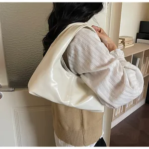 Close-up of a cream-colored patent leather hobo bag with glossy finish and moon shape
