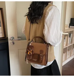 Detalle del bolso tote retro marrón con colgante de oso de peluche y costuras en contraste