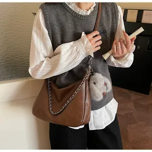 Detail of dark brown matte leather baguette bag with silver chain and plush rabbit charm