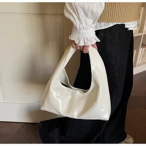 Detail of a creamy white glossy hobo bag with elegant stitching and a polished finish