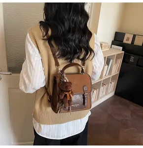 Vista trasera detallada de mochila vintage marrón con colgante de osito de peluche suave
