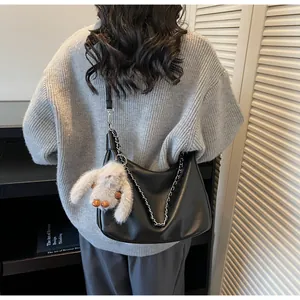 Detail of black leather hobo bag with silver chain and cute plush bunny charm
