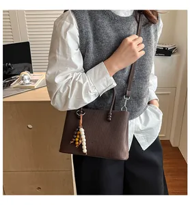 Brown textured leather handbag with wooden bead charm in a lifestyle home setting