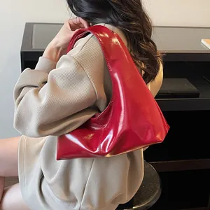 Glossy red patent leather hobo dumpling bag shown on shoulder for daily commute