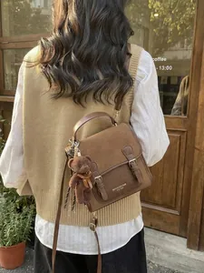 Mochila tote vintage de cuero marrón con colgante de oso en una escena de café urbano