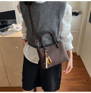 Detail of brown pleated texture handbag with colorful bead pendant and crossbody strap
