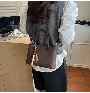 Detail of coffee brown mini tote bag with vertical stripes and beaded tassel charm