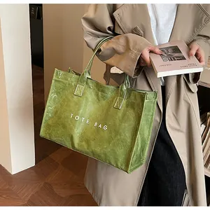 Sac fourre-tout vert en Tyvek avec inscription porté par un mannequin en décor intérieur