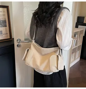Détail du sac cabas crème en cuir texturé avec poches latérales et bandoulière chic