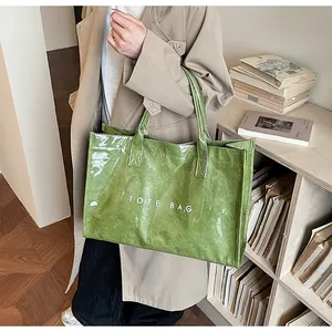 Detail of green glossy tote bag with crinkle texture and white TOTE BAG text print