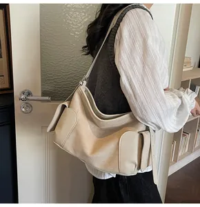 Détail de la texture cuir grainé et poche latérale à rabat d'un sac hobo de couleur beige