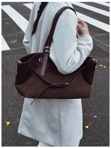 Grand sac cabas en daim marron foncé porté à l'épaule par un mannequin en style décontracté