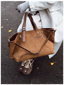 Détail d'un grand sac cabas en daim marron avec boucles métalliques dans un décor urbain