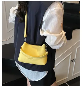 Détail d'un sac à bandoulière en cuir jaune porté par un mannequin en vue arrière
