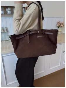 Vue détaillée du grand sac cabas en daim marron foncé porté à l'épaule pour femme