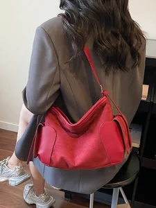 Sac fourre-tout rouge minimaliste en daim avec poches en cuir porté par un mannequin