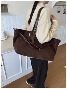 Détail d'un grand sac fourre-tout en daim marron foncé porté à l'épaule par un mannequin