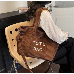 Close-up of brown corduroy tote bag showing striped texture and white TOTE BAG embroidery