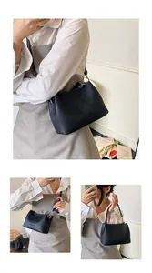 Détail de la texture en cuir grainé noir et du logo embossé sur le sac à bandoulière