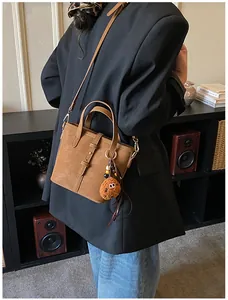 Détail du sac seau en similicuir caramel avec breloque pelucheuse et bandoulière