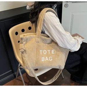 Detailed view of cream corduroy tote bag with TOTE BAG embroidery and adjustable strap