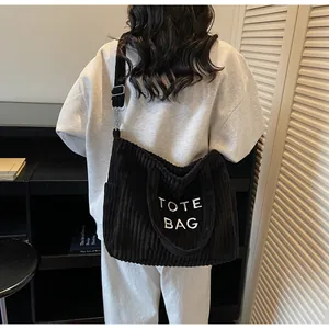 Detail of black corduroy tote bag with TOTE BAG embroidery and adjustable shoulder strap