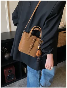 Détail d'un sac seau rétro marron avec sangles décoratives et un charmant biscuit en peluche