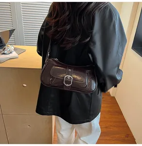 Detail of dark brown leather shoulder bag with vintage silver buckle in an office setting