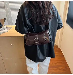 Detail of high-gloss dark coffee patent leather shoulder bag with metallic buckle detail