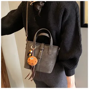 Détail du sac seau gris avec boucle de ceinture et pendentif monstre en peluche orange